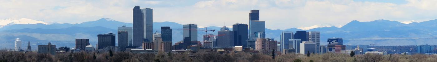 Wide panorama of the Denver skyline with the Rocky Mountains behind it